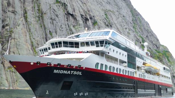 Das Kreuzfahrtschiff „Midnatsol“ fährt vor einer steilen Felswand.