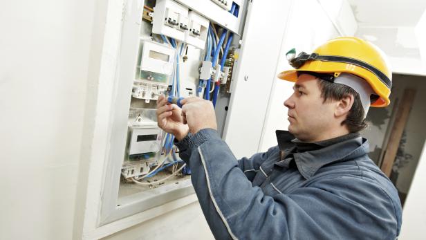 Electrician working on circuit board while wearing helmet