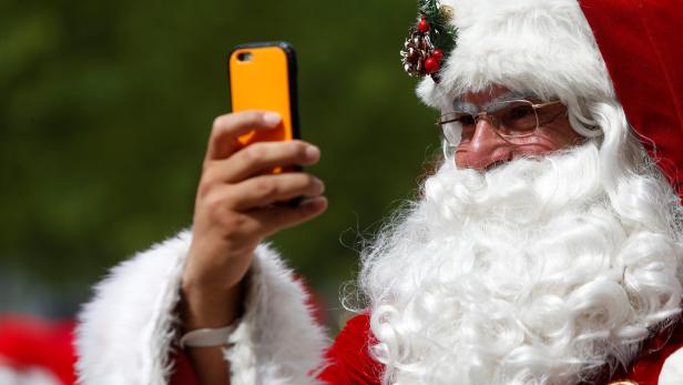 A man dressed as Santa Claus records on his cellphone as he takes part in the World Santa Claus Congress, an annual event held every summer in Copenhagen