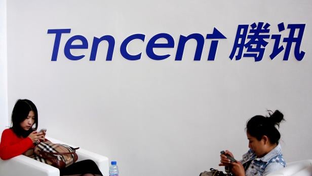 FILE PHOTO: Visitors use phones underneath of logo of Tencent at Global Mobile Internet Conference in Beijing
