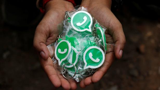 A WhatsApp-Reliance Jio representative displays key chains with the logo of WhatsApp for distribution during a drive by the two companies to educate users, on the outskirts of Kolkata