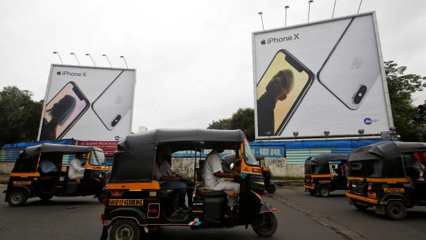 FILE PHOTO: Auto-rickshaws drive past the hoardings of Apple iPhone X mobile phones in Mumbai