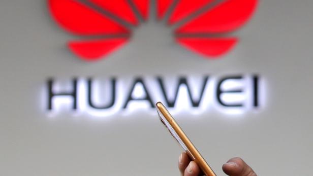 FILE PHOTO: Man holding his phone walks past a Huawei shop in Beijing