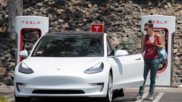 A woman gets into her Tesla electric car at a supercharger station in Los Angeles