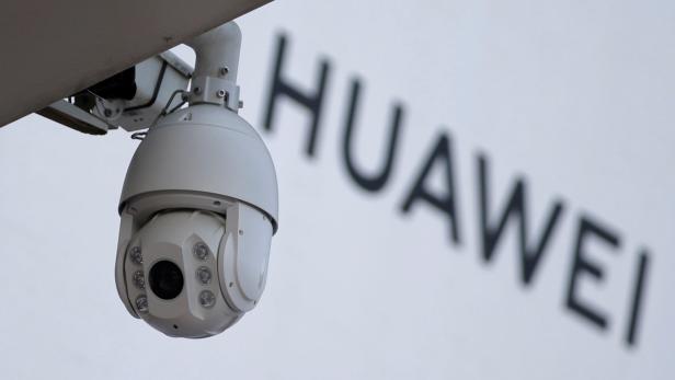 FILE PHOTO: A surveillance camera is seen next to a sign of Huawei in Beijing