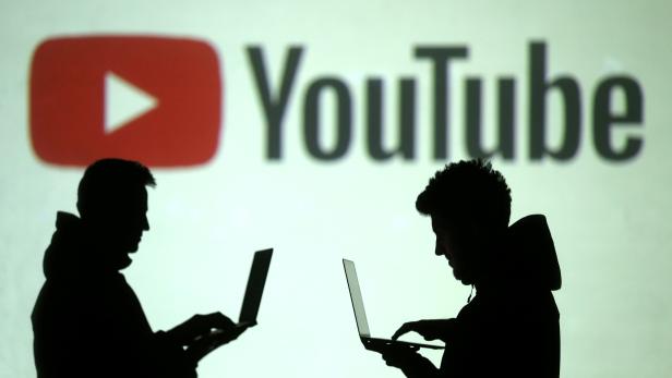 FILE PHOTO: Silhouettes of users are seen next to a screen projection of Youtube logo in this picture illustration