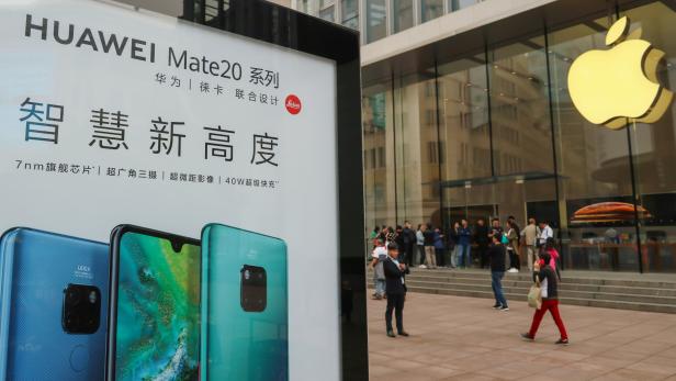 Advertisement for Huawei Mate 20 series is seen outside an Apple store, as customers queue before the store opens on the day the new iPhone XR goes on sale in Shanghai