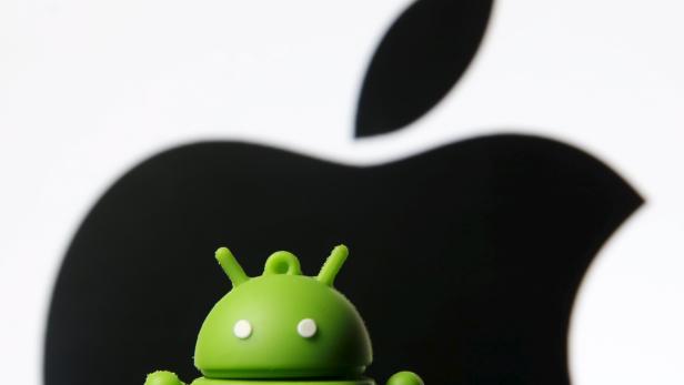 Android mascot is seen in front of a displayed logo of Apple in this photo illustration taken in Zenica