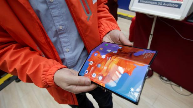 A staff member shows the new Huawei Mate X smartphone with 5G network at the media center for the CPPCC and NPC in Beijing