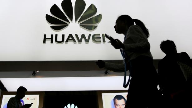 FILE PHOTO: People walk past a sign board of Huawei at CES Asia 2016 in Shanghai