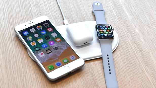 Ein iPhone, eine Apple Watch und AirPods liegen auf einer kabellosen Ladestation.