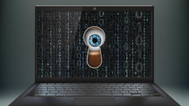 Human eye in the keyhole and a laptop. Cybercrime.