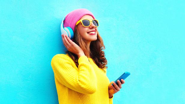 Fashion girl listening to music in headphones with smartphone colorful