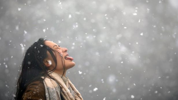 Woman tries to catch snowflakes with her tongue during a snowfall on Chandragiri Hills in Kathmandu