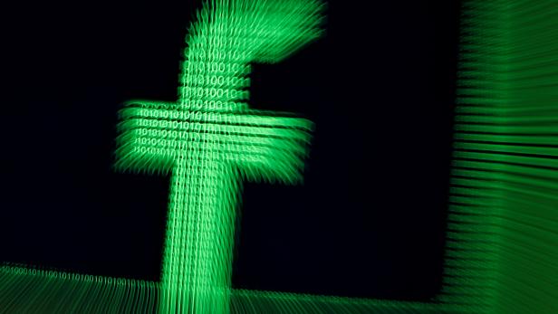 FILE PHOTO: A 3D-printed Facebook logo are seen in front of displayed binary digits in this illustration