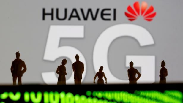 FILE PHOTO: Small toy figures are seen in front of a displayed Huawei and 5G network logo in this illustration picture