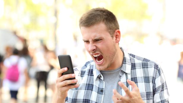 Angry man holding crashed phone