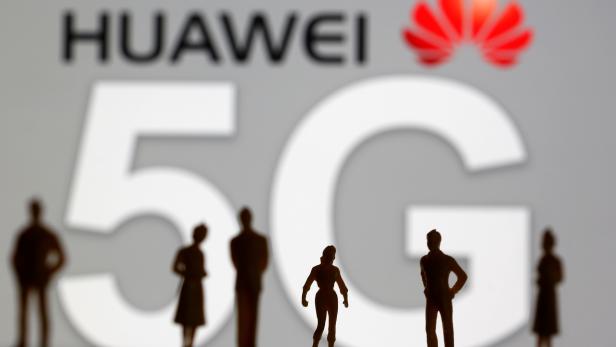 FILE PHOTO: Small toy figures are seen in front of a displayed Huawei and 5G network logo in this illustration picture