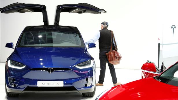 A visitor inspects a Tesla Model X electric vehicle at Brussels Motor Show