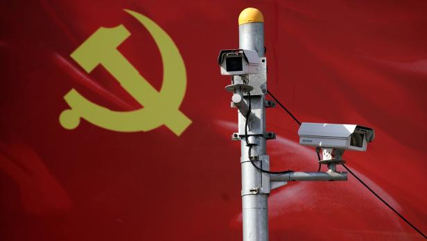 Security cameras are attached to a pole in front of a party flag of Communist Party of China in Shanghai