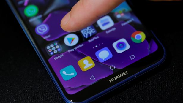 Man points a finger to the Google Play app logo on his Huawei smartphone in this illustration picture