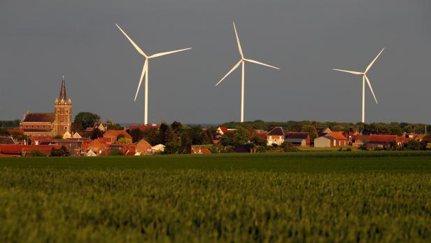 Three power-generating windmill turbines are seen beside the church in Graincourt-les-Havrincourt