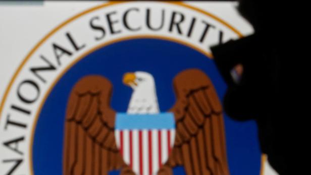 FILE PHOTO: A man is silhouetted near logo of the U.S. National Security Agency (NSA) in this photo illustration taken in Sarajevo