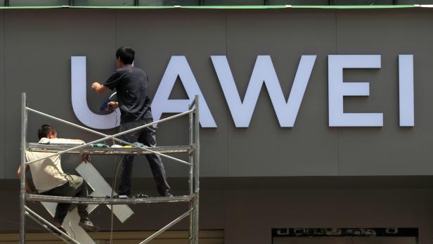 Workers put up a sign for a new Huawei store under construction in Kunming