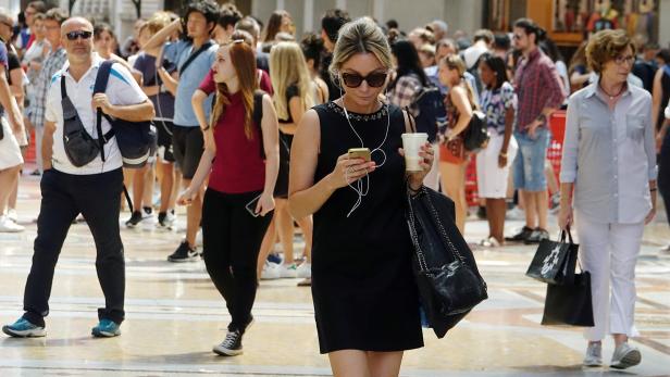 FILE PHOTO: A woman checks on her mobile phone downtown Milan, Italy