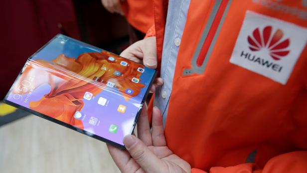 A staff member shows the new Huawei Mate X smartphone with 5G network at the media center for the CPPCC and NPC in Beijing