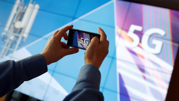 FILE PHOTO: FILE PHOTO: A journalist uses his mobile phone to take a picture of the 5G logo prior to the auction of spectrum for 5G services at the Bundesnetzagentur head quarters in Mainz