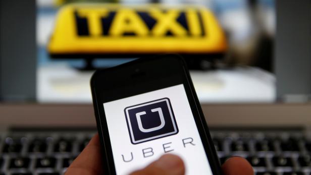 FILE PHOTO: An illustration picture shows the logo of car-sharing service app Uber on a smartphone next to the picture of an official German taxi sign