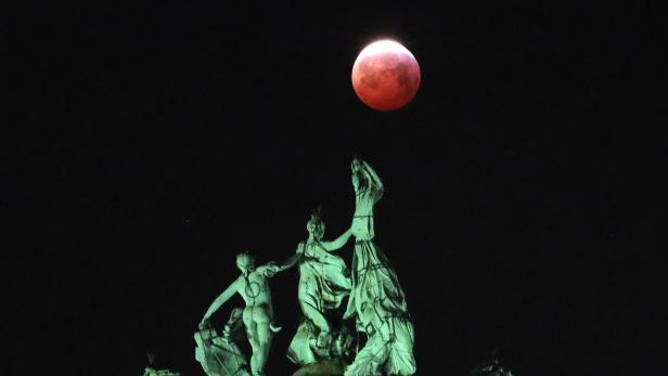 The moon is seen beside a quadriga on the top of the Cinquantenaire arch during a total lunar eclipse known as the "Super Blood Wolf Moon", in Brussels