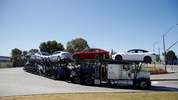 FILE PHOTO: A car carrier trailer carries Tesla Model 3 electric sedans, is seen outside the Tesla factory in Fremont