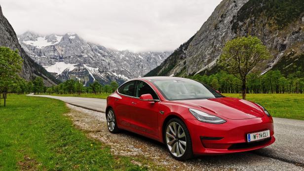 Ein rotes Tesla-Auto vor einer Berglandschaft.
