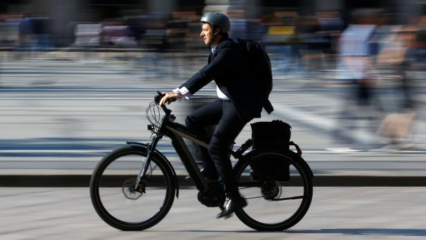 A man rides an electric bicycle, also known as an e-bike, in downtown Milan