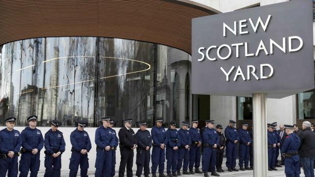 Police officers observe a moment's silence outside New Scotland Yard in Westminster the day after an attack, in London