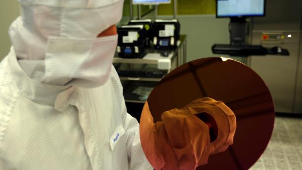 FILE PHOTO: An employee is reflected in a wafer inside a clean room of German semiconductor manufacturer Infineon in Regensburg