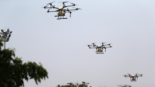 Drones fly and spray water during an operation to reduce air pollution in Bangkok