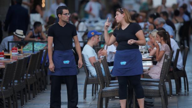 A waitress and a waiter chat as they wait for customers at the terrace of a restaurant in downtown Ronda
