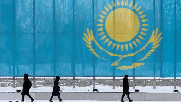 People walk past a gaint Kazakhstan's flag in Astana
