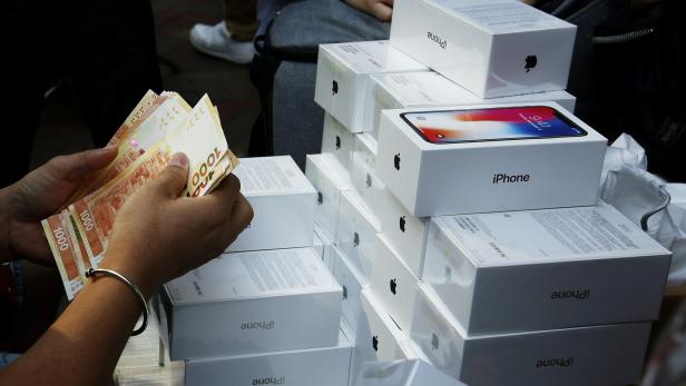 FILE PHOTO: A man pays to buy new iPhone Xs from those who just bought at Apple Stores, on a street in Hong Kong