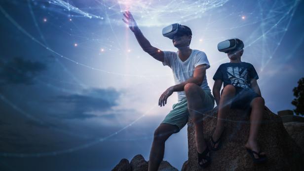 Father and son using Virtual Reality glasses sitting outside