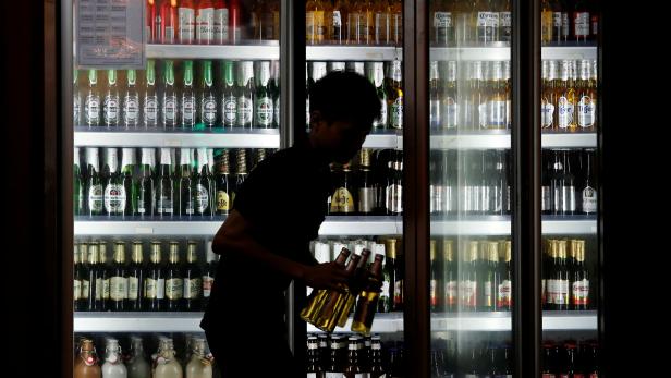 A man takes bottles of tiger beer out of a beer fridge at a restaurant in Hanoi