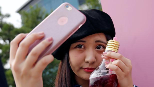 A woman takes a selfie with a drink from FOOD BOAT cafe during the Photogenic Sweets Festa at a shopping mall in Tokyo