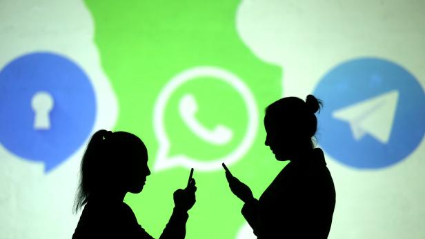 Silhouettes of mobile users are seen next to logos of social media apps Signal, Whatsapp and Telegram projected on a screen in this picture illustration