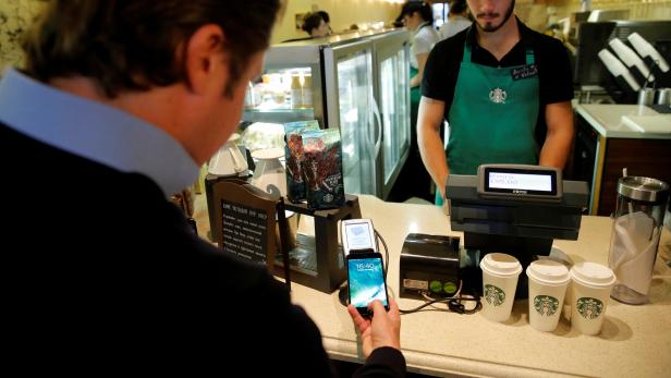 Man uses iPhone 7 smartphone to demonstrate mobile payment service Apple Pay at cafe in Moscow