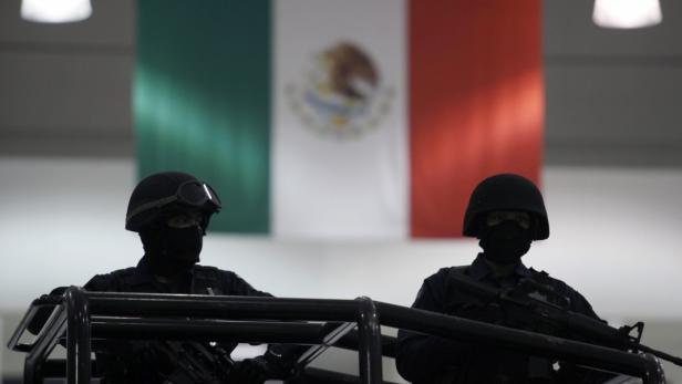 Mexican federal police stands guard as suspected members of the Sinaloa drug cartel are presented during a news conference at the federal police center in Mexico City August 12, 2010. The suspects were arrested on Thursday in connection to the kidnapping of two television journalists by members of the Sinaloa cartel, Mexico&#039;s most powerful drug trade organization, according to the police. The journalists were freed by the federal police on July 30. REUTERS/Eliana Aponte (MEXICO - Tags: MEDIA CIVIL UNREST CRIME LAW SOCIETY)