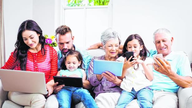 Family using technologies while sitting in sofa