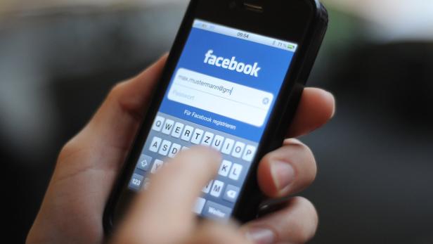 Mensch tippt seine Login-Daten für Facebook auf dem Smartphone ein